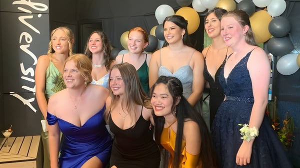 Eine Gruppe von Schülerinnen der Ballina Coast High School posiert in formeller Kleidung vor Luftballons bei einer Feier.