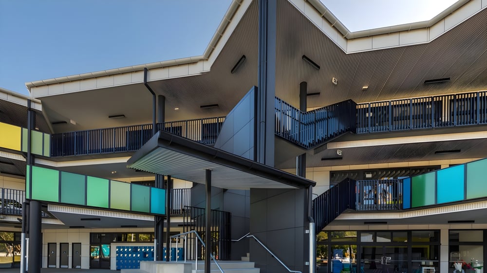 Das farbenfrohe, moderne Schulgebäude der Ballina Coast High School mit Balkonen und Treppen vor blauem Himmel.