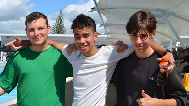 Drei Schülerinnen und Schüler stehen zusammen im Freien auf dem Campus der Ballina Coast High School.