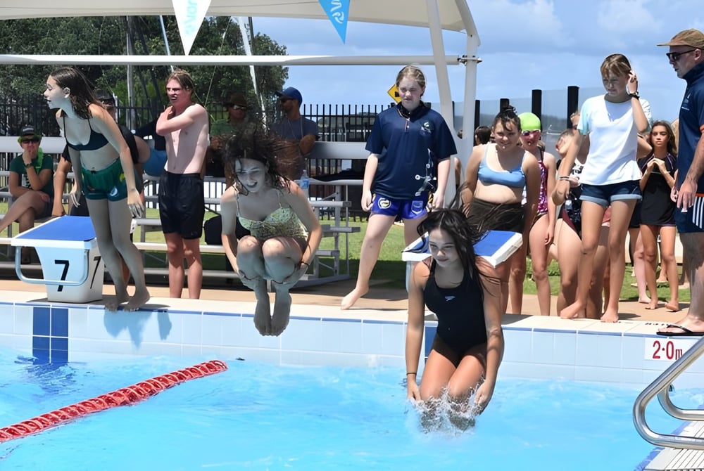 Eine Gruppe von Schülerinnen und Schülern der Ballina Coast High School steht am Schwimmbad und einige sind im Wasser.