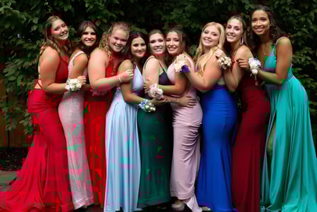 Eine Gruppe junger Schülerinnen der Ballingarry Presentation School steht im Freien auf einer grünen Wiese in bunten formellen Kleidern.