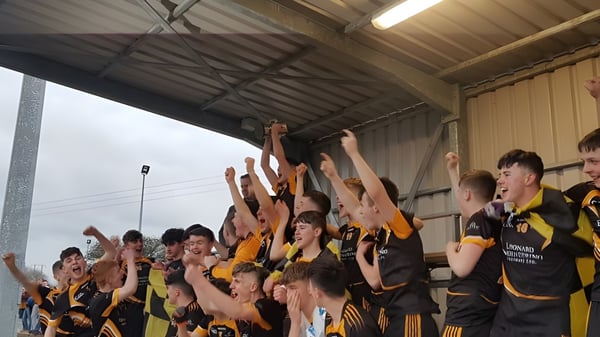 Schüler des Ballybay Community College heben in einer Sporthalle ihre Arme in gemeinsamer Feier.