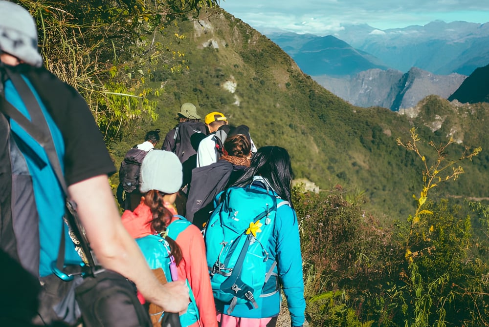 Eine Gruppe von Schülerinnen und Schülern vom Ballybay Community College wandert auf einem schmalen Bergpfad mit beeindruckender Berglandschaft im Hintergrund.