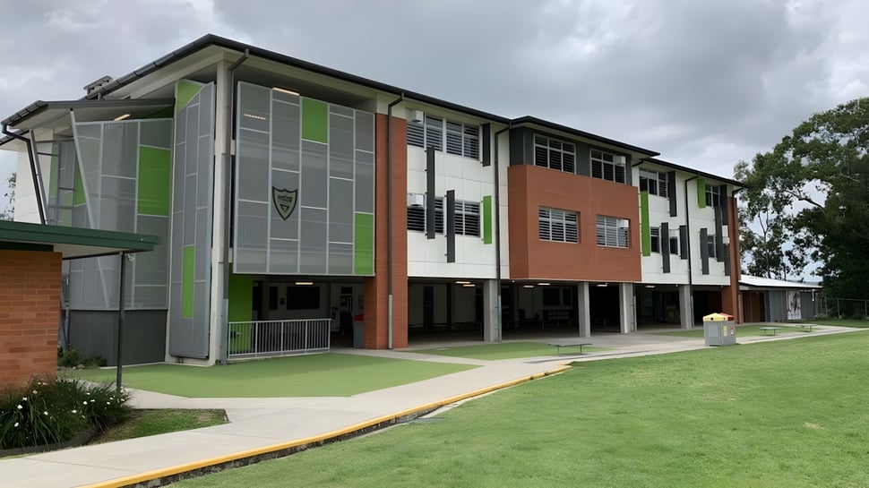 Das moderne mehrstöckige Gebäude der Ballymahon Vocational School steht auf einer grünen Wiese und ist von Bäumen umgeben.