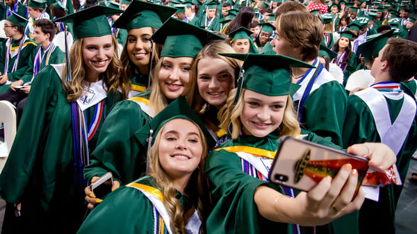 Eine Gruppe von Absolventinnen und Absolventen der Balmoral State High School in grünen Abschlussroben macht gemeinsam ein Selfie.