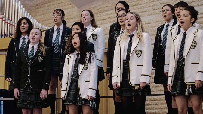 Schüler der Balmoral Hall High School stehen vor einer großen Pfeifenorgel in einem Schulgebäude.