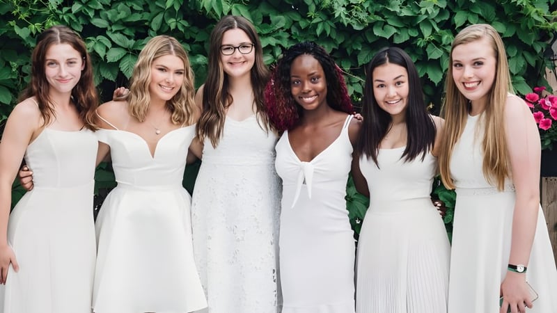 Sechs Schülerinnen der Balmoral Hall High School stehen vor einer grünen Pflanzenwand.