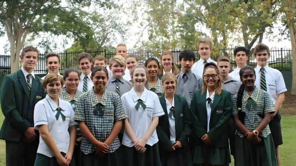 Eine Gruppe von Schülerinnen und Schülern der Balmoral State High School steht draußen vor Bäumen und einem Zaun.
