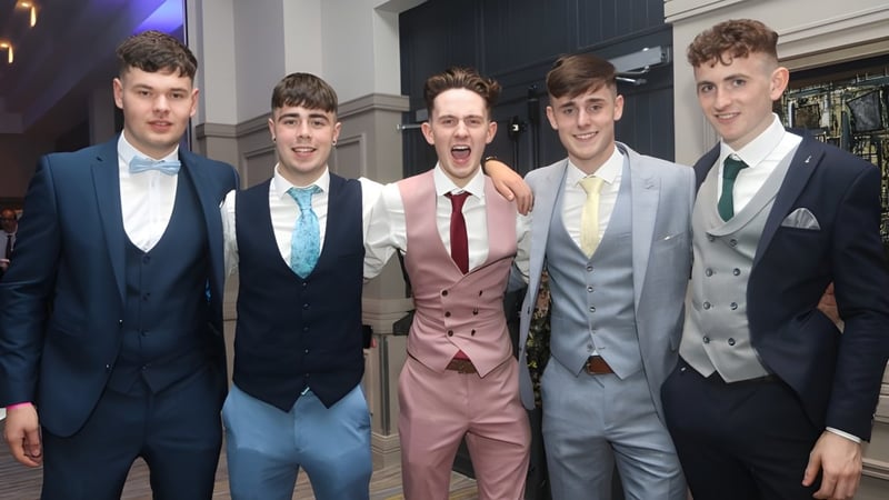 Eine Gruppe von Schülern des Banagher College posiert bei einer formellen Veranstaltung vor dunklem Hintergrund mit Bühnenbeleuchtung.