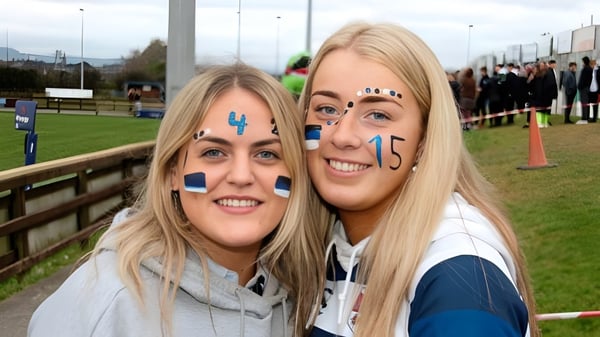 Zwei Schülerinnen der Bandon Grammar School mit bemalten Gesichtern bei einer Sportveranstaltung im Freien.