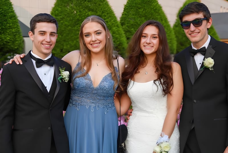 Vier junge Erwachsene der Bandon Grammar School posieren gemeinsam in einem Garten mit grünen Pflanzen und Blumen.