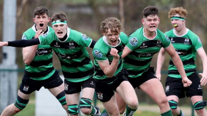 Eine Gruppe junger Rugby-Spieler in grünen und schwarzen Trikots trainiert auf dem Sportplatz der Bandon Grammar School.
