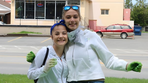 Zwei Schülerinnen der Banting Memorial High School stehen vor einem Gebäude mit parkenden Autos im Hintergrund.