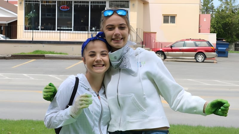 Zwei Schülerinnen der Banting Memorial High School stehen vor einem Gebäude mit parkenden Autos im Hintergrund.