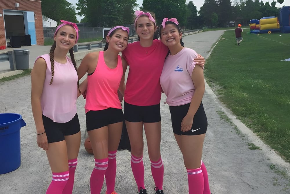 Eine Gruppe junger Schülerinnen der Banting Memorial High School steht im Freien auf einem Sportplatz.