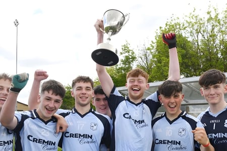 Schüler des Bantry Community College feiern auf dem Sportfeld mit einem Pokal in der Hand.