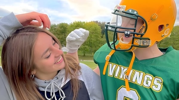 Eine Person im grünen Vikings-Sporttrikot steht neben einer weiteren Person auf dem Gelände des Barrie North Collegiate Institute.