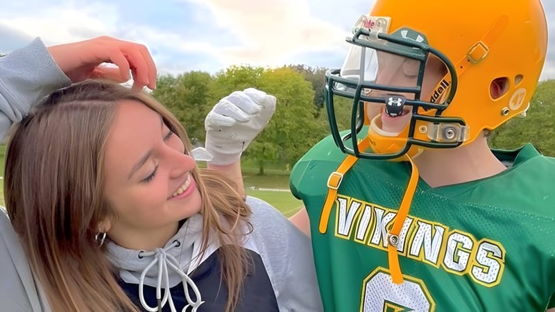 Eine Person im grünen Vikings-Sporttrikot steht neben einer weiteren Person auf dem Gelände des Barrie North Collegiate Institute.