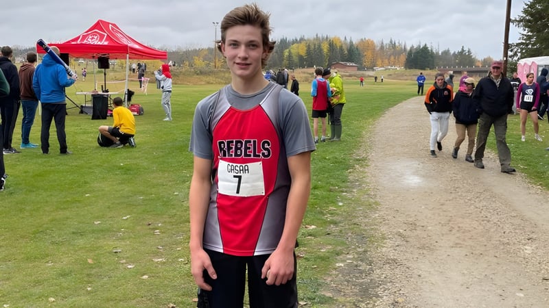 Ein Schüler der Bashaw School steht auf einem Feldweg mit Zelt und weiteren Personen im Hintergrund.