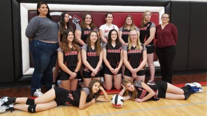 Eine Gruppe Schülerinnen der Bashaw School posiert gemeinsam in Sportuniformen in einer Turnhalle.