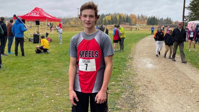 Ein Schüler der Bashaw School steht auf einem Weg neben einem Sportplatz mit einem roten Zelt im Hintergrund.
