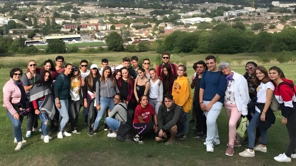 Eine Gruppe von Schülerinnen und Schülern der Bath Academy versammelt sich auf einer Wiese mit Blick auf eine Stadt im Hintergrund.