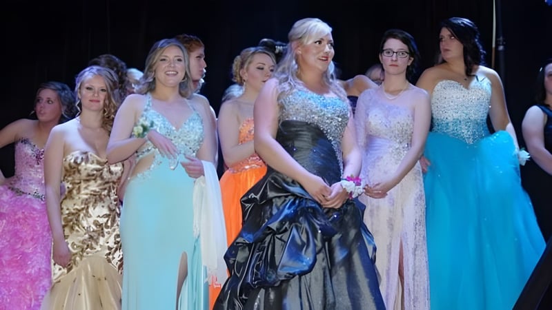 Eine Gruppe junger Frauen in formellen Abendkleidern steht auf der Bühne der Bawlf School.