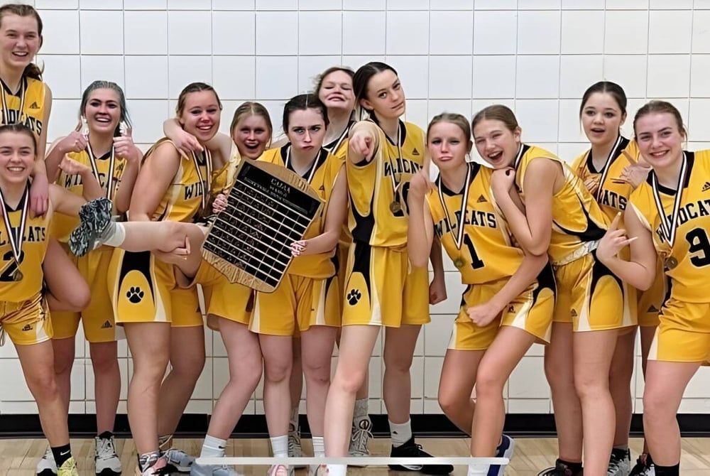 Eine Gruppe junger Basketballspielerinnen in gelben Trikots posiert an der Bawlf School vor einer gefliesten Wand.