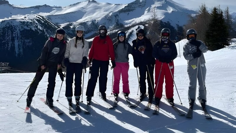 Eine Gruppe von Schülern der Bawlf School steht im Winter auf einem schneebedeckten Hang mit Bergen im Hintergrund.
