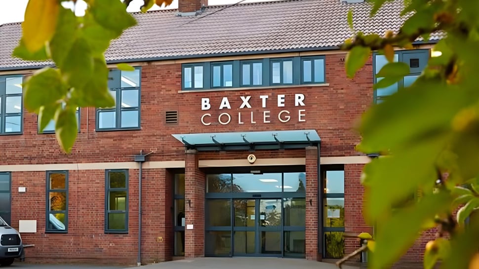 Das Backsteingebäude des Baxter College ist umgeben von üppigem Grün und Bäumen im Vordergrund.
