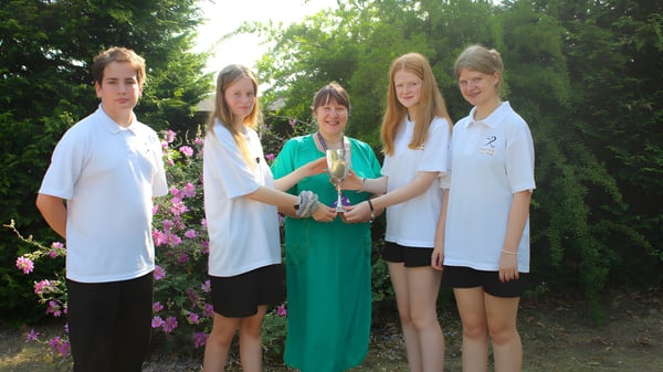 Eine Gruppe von fünf Schülerinnen und Schülern steht in einem grünen Außenbereich auf dem Campus des Baxter College.