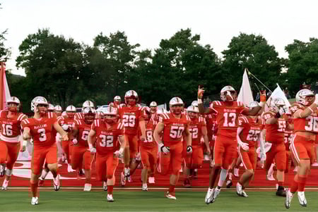 Eine Gruppe von Fußballspielern in roten Trikots läuft über das Spielfeld auf dem Gelände der Baylor School.