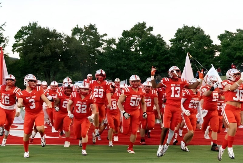 Eine Gruppe von Fußballspielern in roten Trikots läuft über das Spielfeld auf dem Gelände der Baylor School.