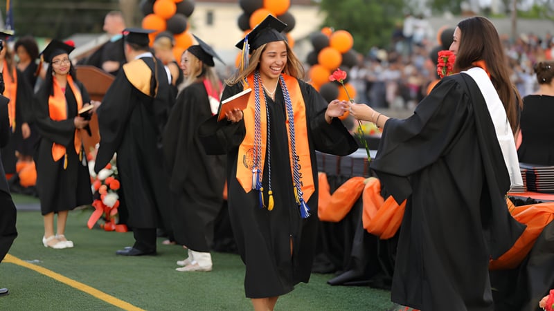 Eine Gruppe von Absolventinnen und Absolventen in schwarzen Talaren auf der Abschlussfeier der Bayridge Secondary School auf einer Wiese.