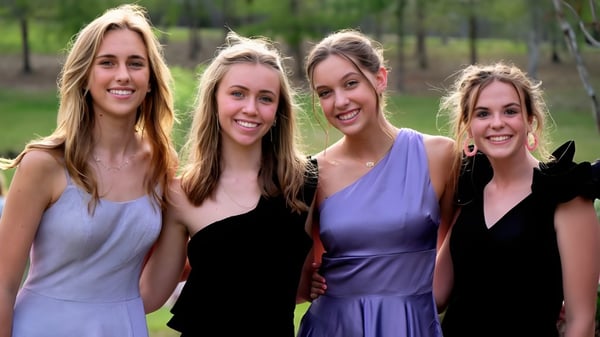 Vier Schülerinnen stehen lächelnd auf einer Wiese mit Bäumen auf dem Gelände der Bayshore Christian School.