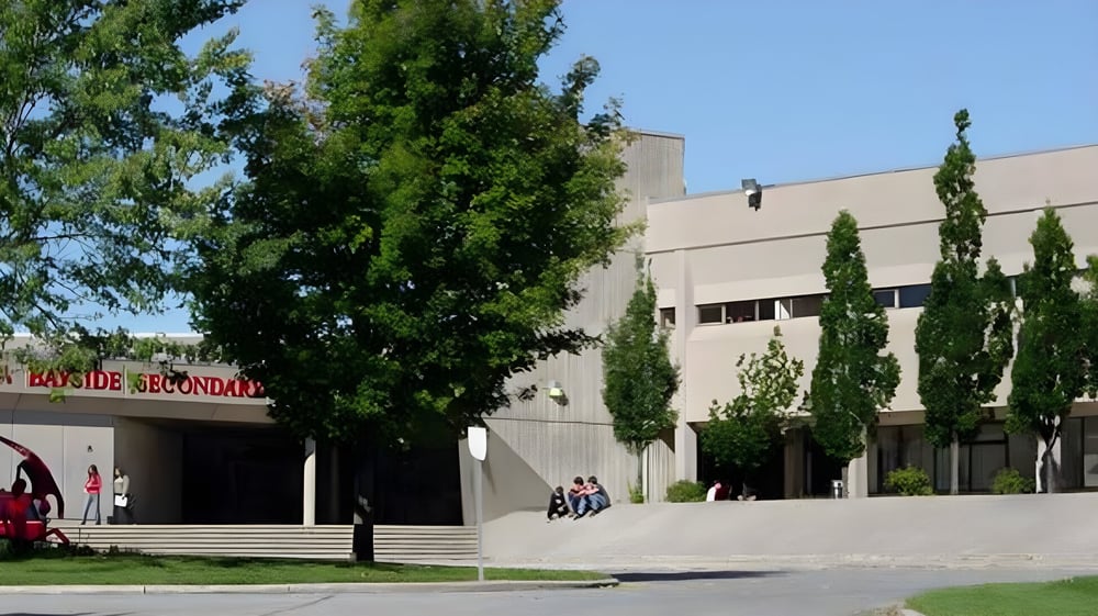 Das mehrstöckige moderne Gebäude der Bayside Secondary School ist von Bäumen und grüner Anlage umgeben.