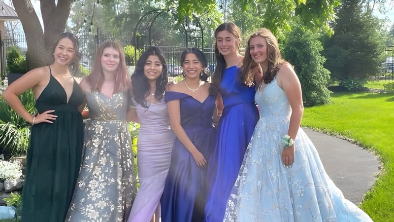 Fünf Schülerinnen der Bayside Secondary School stehen in farbigen Kleidern zusammen im grünen Außenbereich der Schule.