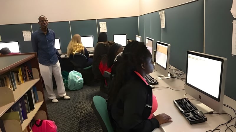 Schüler der Beacon of Hope Christian School lernen an Computern in einem Klassenraum mit Tafel und Bücherregalen.