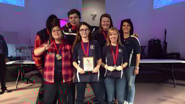 Eine Gruppe von Schülerinnen und Schülern der Beacon of Hope Christian School steht auf der Bühne mit Musikinstrumenten und Lichttechnik im Hintergrund.