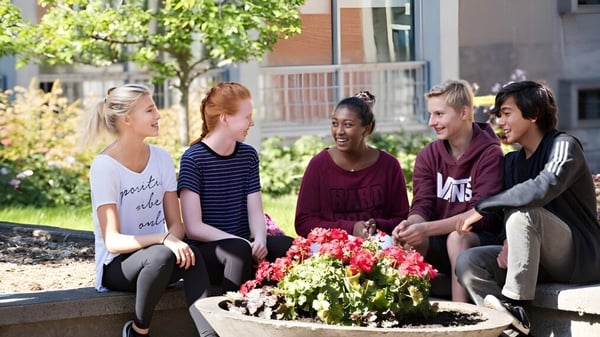 Eine Gruppe Schülerinnen der Beaconsfield High School sitzt auf einer Gartenbank umgeben von bunten Blumen und Grünpflanzen.