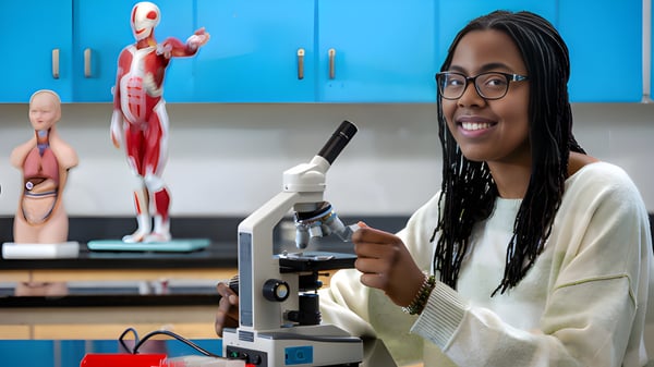 Eine Schülerin der École Secondaire Beaumont Composite High School nutzt ein Mikroskop im Klassenzimmer mit anatomischen Modellen im Hintergrund.