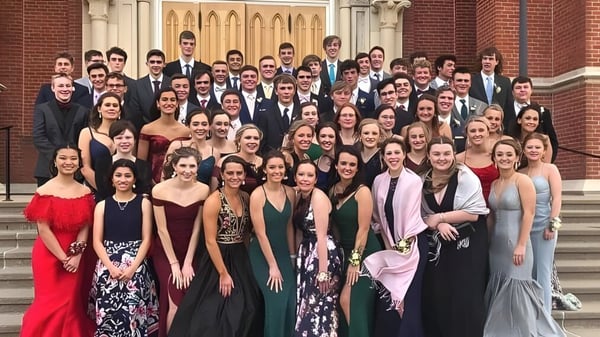 Eine große Gruppe von Schülerinnen und Schülern der Beckman Catholic School versammelt sich in formeller Kleidung auf der Treppe eines historischen Gebäudes.