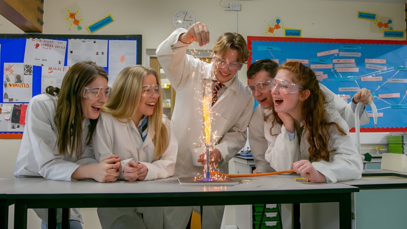 Schüler der Bede's Senior School führen in Laborkitteln ein Experiment mit farbigem Feuer durch.