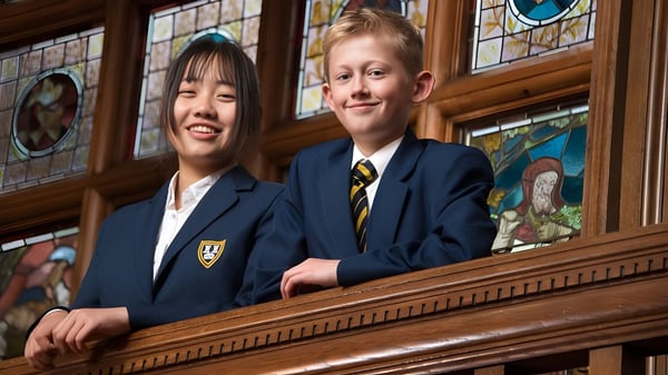 Zwei Schüler stehen vor einer Holzstruktur mit bunten Glasfenstern auf dem Campus des Bedstone College.