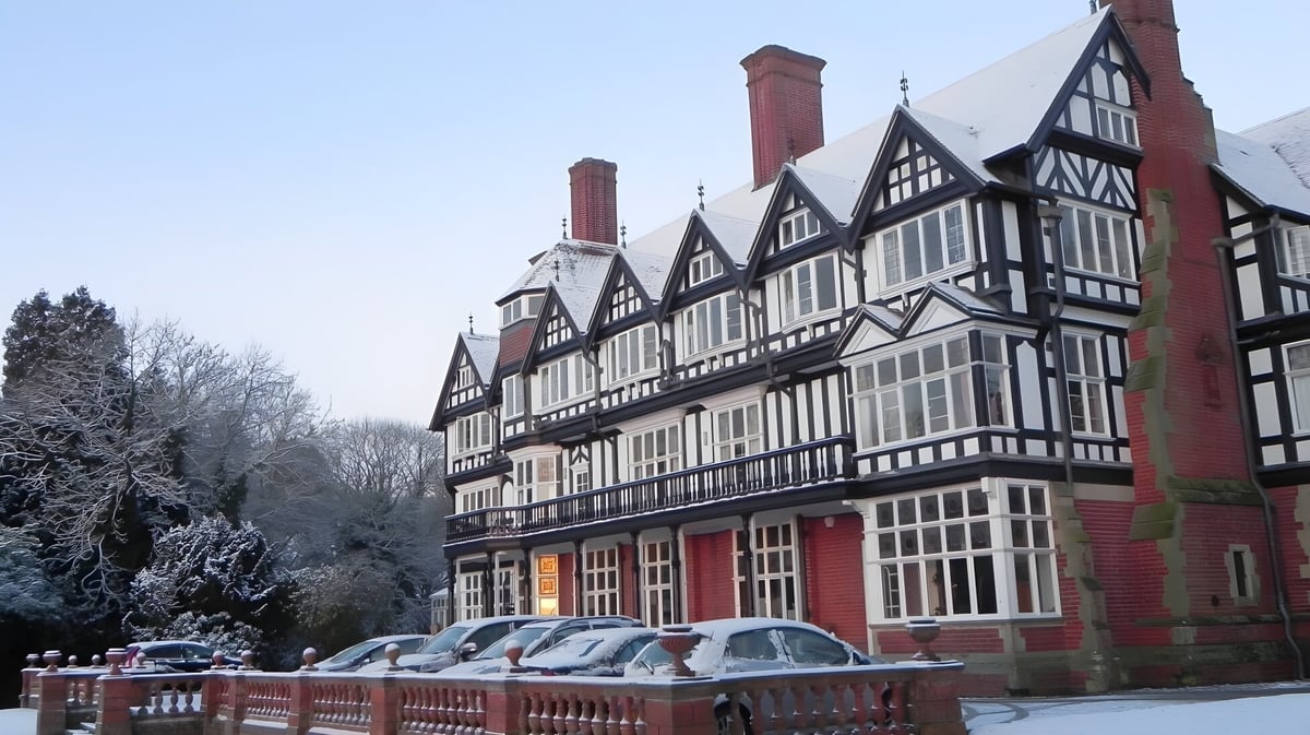 Das historische Tudor-Gebäude von Bedstone College ist von schneebedeckten Bäumen und klarem blauem Himmel umgeben.