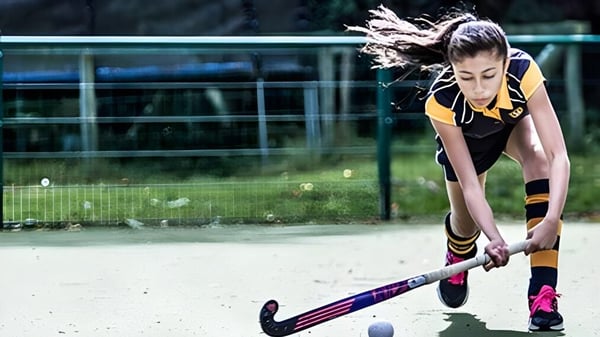 Eine junge Sportlerin der Bedstone School konzentriert sich auf den Hockeyball auf dem Sportplatz.