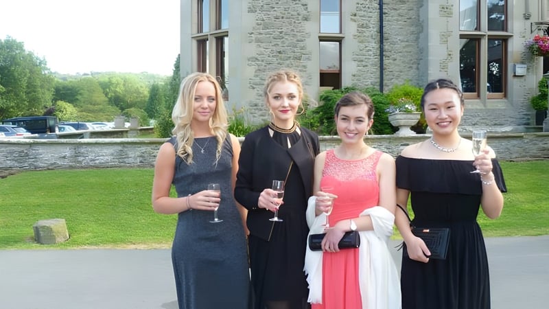 Vier Schülerinnen der Bedstone School stehen zusammen vor einem steinernen Gebäude mit viel Grün.