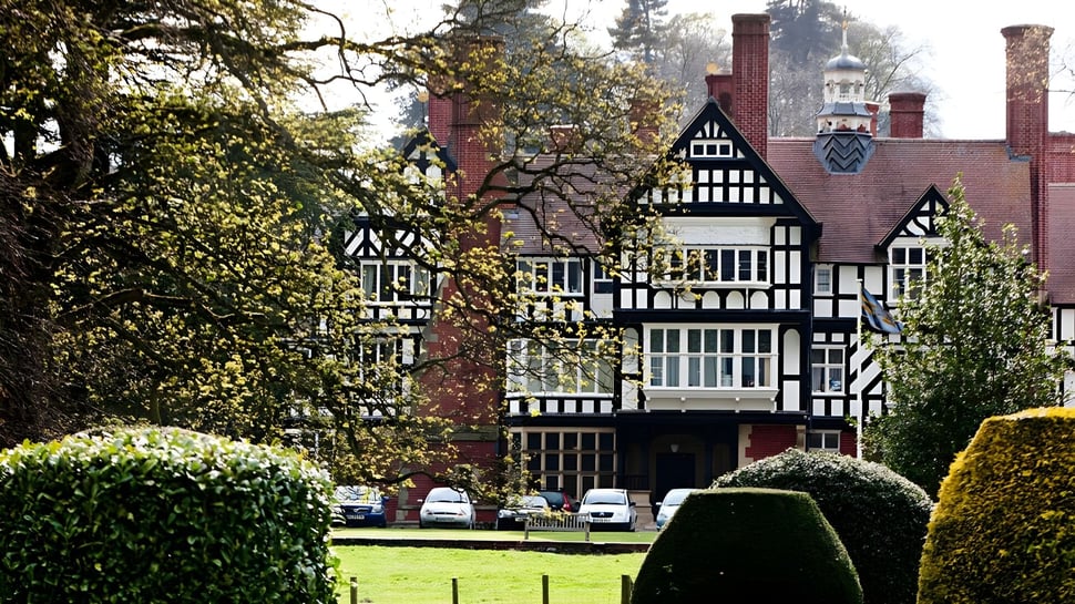 Das Tudor-Stil Herrenhaus mit gepflegtem Rasen und Bäumen auf dem Gelände der Bedstone School.