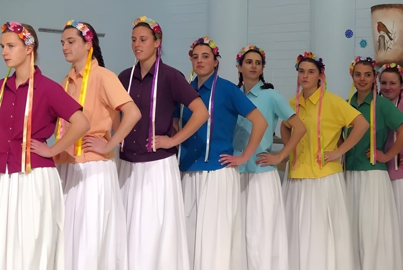 Schülerinnen der Beech Grove School stehen in bunten traditionellen Kleidern auf einer Bühne.