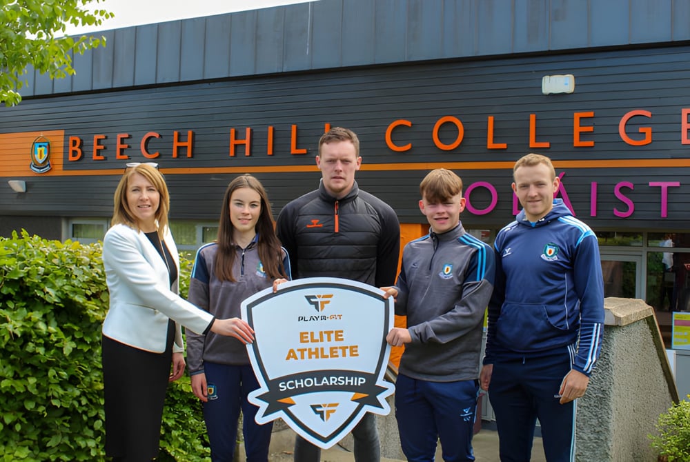 Schüler und Mitarbeiter stehen vor dem Gebäude des Beech Hill College und halten ein Schild mit der Aufschrift Elite Athlete Scholarship.